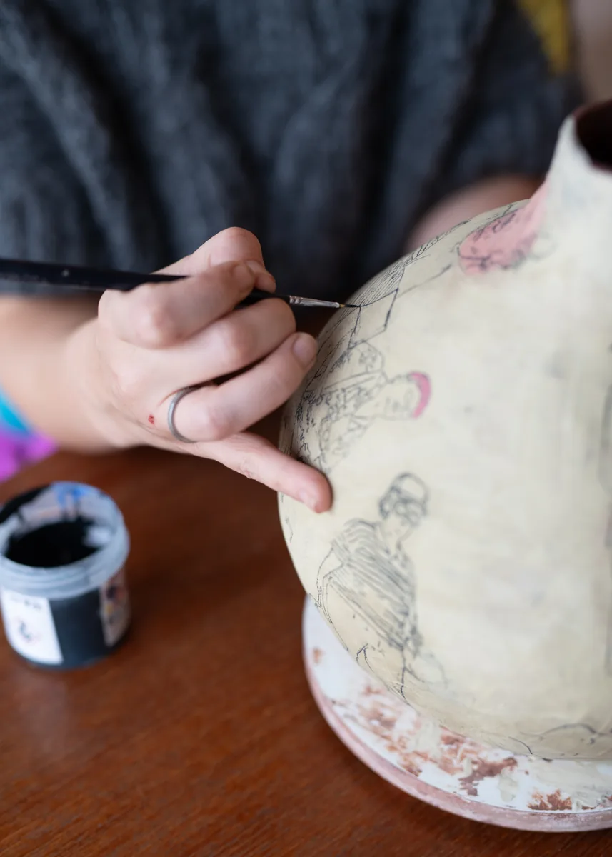 Suzanne Dolan's hand with a brush on a vessel